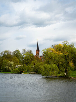 Church spire over a lakeside in Birzai, Lithuania