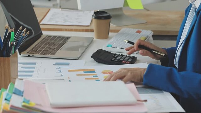 Close up of businessman or accountant hand holding pen working on calculator to calculate business data, accountancy document and laptop computer at office, business concept