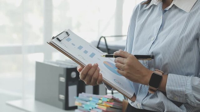 Close up of businessman or accountant hand holding pen working on calculator to calculate business data, accountancy document and laptop computer at office, business concept