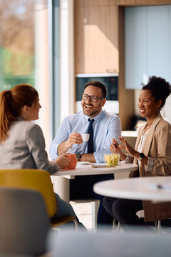 Group of happy business colleagues communicating at office cafeteria.