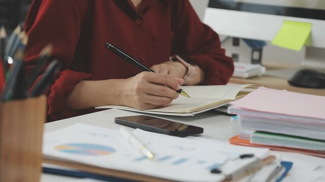 Close up of businessman or accountant hand holding pen working on calculator to calculate business data, accountancy document and laptop computer at office, business concept