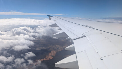 Fototapeta premium View from airplane window with wing, clouds over Fuerteventura, Canary Islands, Spain. 
