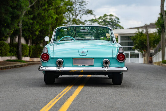 Turquoise Ford Thunderbird centered rear view with open top, Classic convertible car on asphalt road