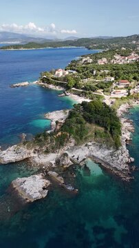 Kassiopi, Corfu, Greece: Scenic view of the traditional fishing port and turquoise Ionian Sea. Beautiful Mediterranean village landscape with boats and coastal architecture on a sunny summer day.