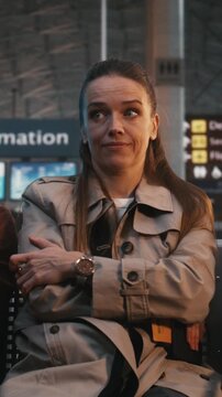 Highly Sensitive Passenger Sits Amidst Chaos of Terminal, Showing Signs Sensory Processing Struggle. Woman Remains Still and Focused, Regulating Emotions Against Loud Environment. Vertical Shot.
