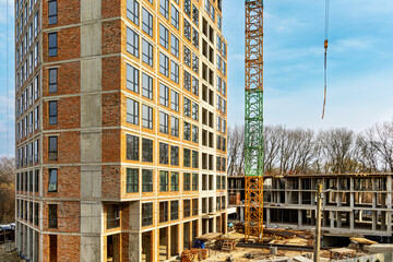 High Rise Building Under Construction With Crane. Partially completed multi story building beside a tower crane at an active construction site. © Iryna