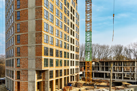 High Rise Building Under Construction With Crane. Partially completed multi story building beside a tower crane at an active construction site.