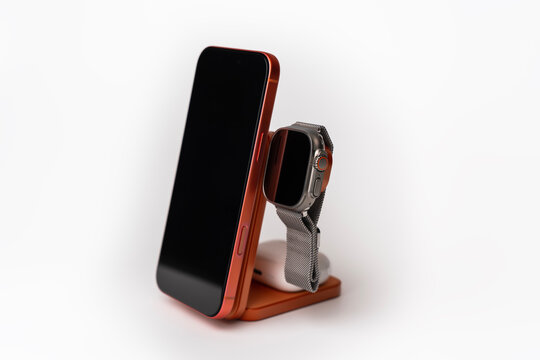 Wireless charging station with a smartphone, smartwatch and headphones. Wireless charging station with a trendy orange smartphone. Technology and wireless charging concept