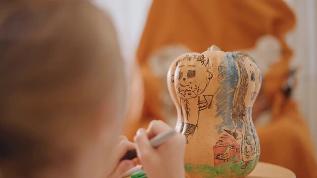 Young girl painting pumpkin gourd, closeup of hands with small brush creating detailed patterns, warm orange blanket backdrop, soft window light, cozy tabletop craft session with palette and careful