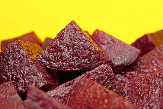 Red boiled beetroot cut into pieces on yellow background