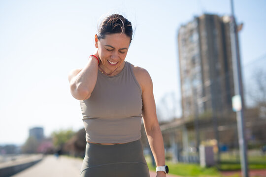 Female runner feeling neck pain after workout outdoors