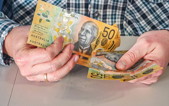 Male hands showing fan of Australian fifty dollar banknotes AUD currency for travel or payout