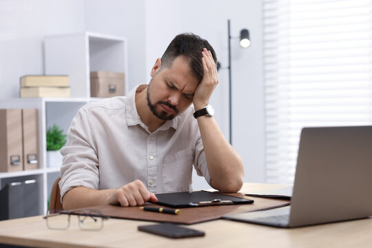 Man feeling fatigue at wooden desk in office