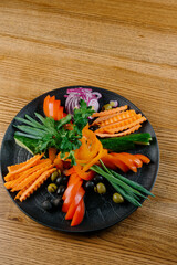 Colorful vegetable platter with fresh herbs on a black plate © Alexander