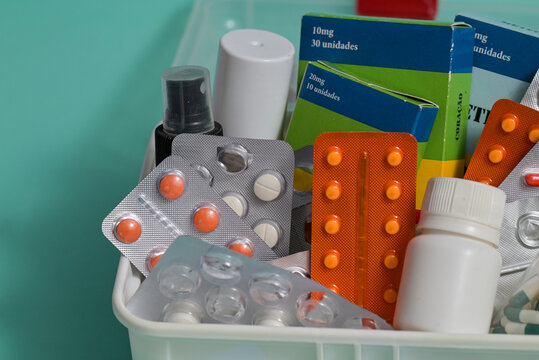 Diverse collection of pharmaceutical products such as tablets in blister strips, medicine boxes, and plastic bottles neatly organized in a white storage bin for home healthcare