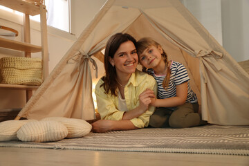 Mother and her daughter in toy wigwam at home © New Africa