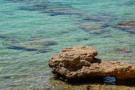 Rock in shallow clear turquoise seawater