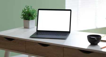 Fototapeta premium Laptop, cup of drink, floral decor and stationery on white desk in office, closeup