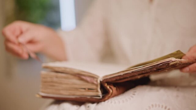 White woman examining antique book ribbon, careful hand lifts silk bookmark from worn pages, closeup on textured spine and parchment, focused archival study, quiet curiosity and methodical motion,