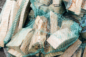 Pile of firewood logs wrapped in green netting © KEA