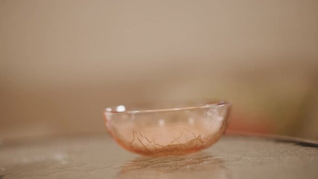 Closeup glass bowl with pumpkin puree residue on glossy countertop, warm bokeh background, cinnamon flecks and crumbs, home baker finishing pie prep, rustic autumn atmosphere, soft golden light