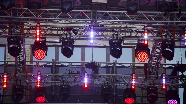 Modern stage lighting rig with LED spotlights and truss system. Equipment prepared for live concert or festival. Event production industry concept. Bright red and white lights.