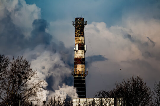 Industrial smokestack emitting steam against cloudy sky