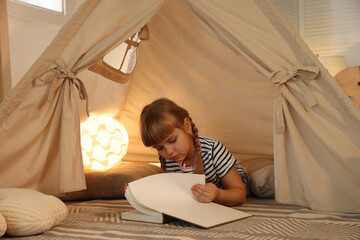 Little girl with book in wigwam at home © New Africa