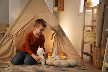 Little boy playing with toys near wigwam at home © New Africa