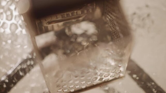 Chef demonstrates citrus zesting technique. Closeup of grater motion over bowl showing beautiful zesting process. Chef skillfully demonstrates how to grate orange peel over warm porcelain bowl