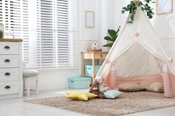 Toy wigwam with pillows, furniture and floral decor in room, space for text © New Africa