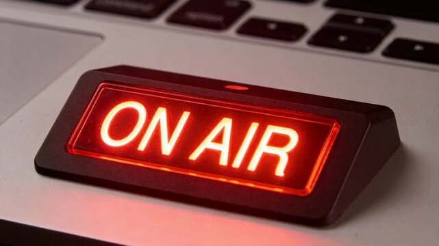 Glowing ON AIR sign sitting on laptop palm rest at desk, indicating live broadcast since start