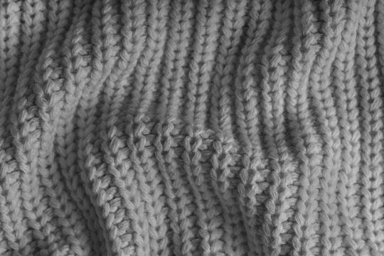 Close up, macro of crumpled gray knitted fabric with visible wrinkles, folds and soft waves. Soft wool texture with detailed stitches and creases, natural textile background, fashion, design
