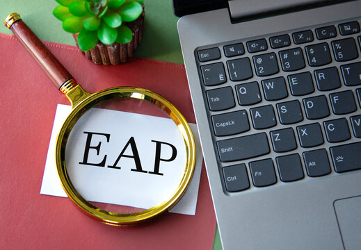 EAP - acronym on a white sheet under a magnifying glass next to a laptop