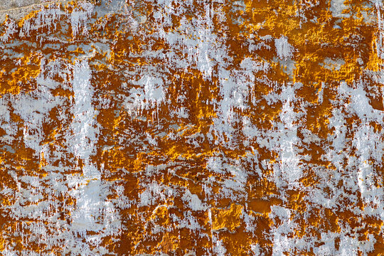 Abstract textured wall with peeling orange paint in Menorca