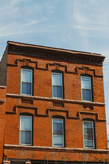 Obraz premium Brick building with windows and decorative elements in a city setting under a clear blue sky during the day