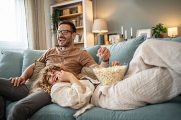 Happy young couple laughing watching movie at home