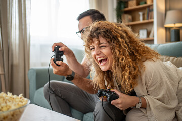 Couple laughing while enjoying fun video game competition © Migma_Agency