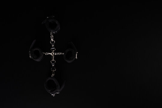 Metal handcuffs with chains arranged on black background with copy space, flat lay composition.