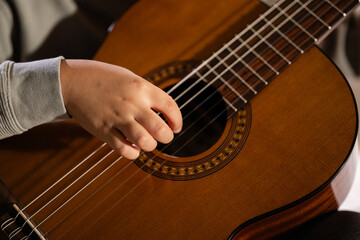 Fototapeta premium Hand strumming classical guitar strings learning music