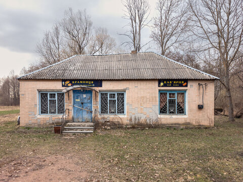 Abandoned rural shop building with cafe sign and damaged entrance. Rudnia-Hatskivka, Zhytomyr Oblast, Ukraine, March 28, 2026.