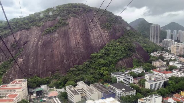 Scenic Cable Car Ride Above Lush Green Mountains and Urban Area Rio de Janeiro Brazil zoom out and panning left