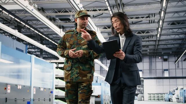 Soldier collaborating with microchip production factory manager about using microelectronics for national security operation. Army officer and Asian man talk about semiconductor supply chain