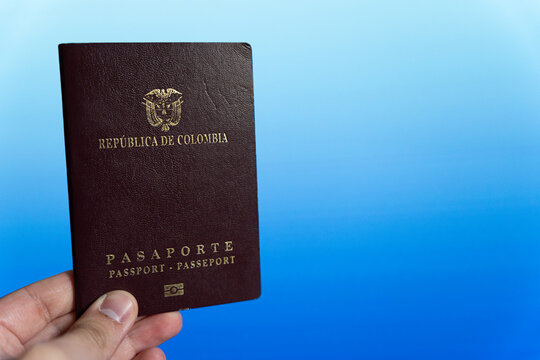 A Colombian passport in hand on a blue background
