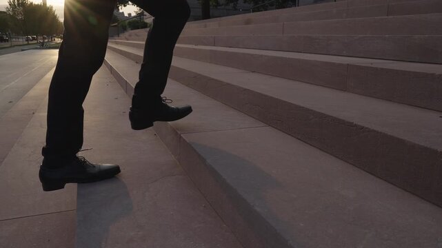 Business man moving up stairs toward success. Businessman walking stairs in urban setting. Business man climbing stairs as career journey. Businessman stepping higher on stairs.