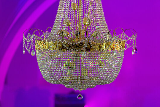 Crystal chandelier sparkling against vivid purple uplighting