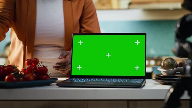 Mockup chroma key on laptop screen with vlogger filming cooking process, behind the scenes with content creator making a recipe at home studio in rustic kitchen. Homemade food.