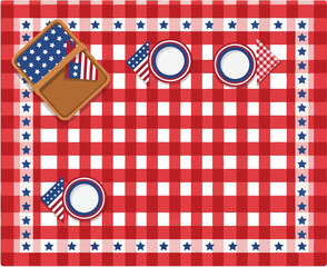 Fototapeta premium Overhead view of a red and white gingham picnic tablecloth set with plates, small flags, and an open basket for outdoor dining.
