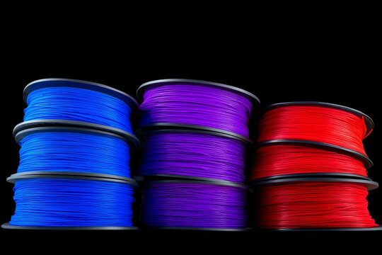 Stacks of colorful 3d printing filament spools in blue, purple, and red