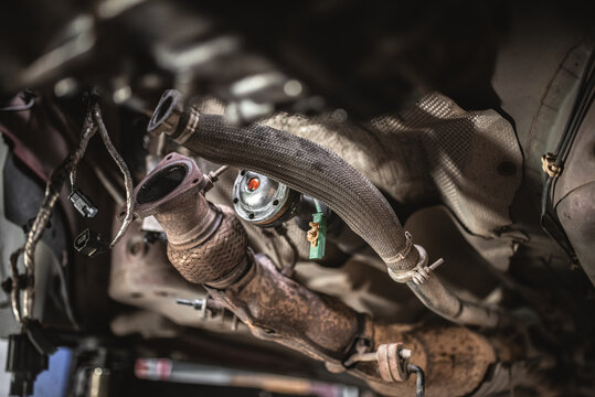 Close-up view of a rusty catalytic converter and exhaust system components on a car